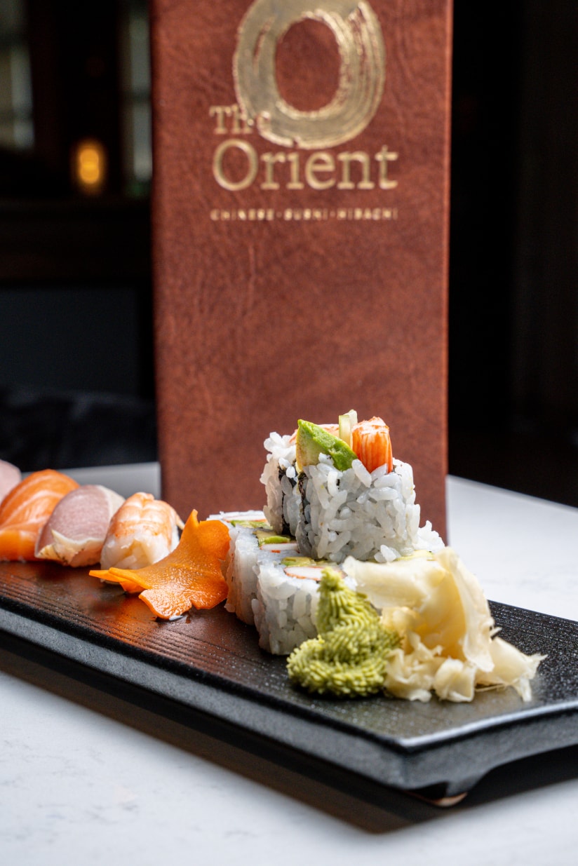 Nigiri and rolls on a slate plate, in front of a leather The Orient menu