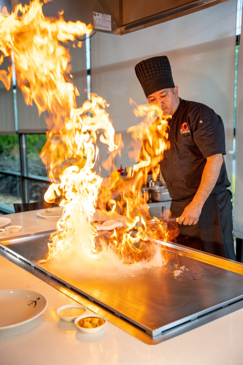 A hibachi chef sending up a wall of flame at the teppanyaki grill