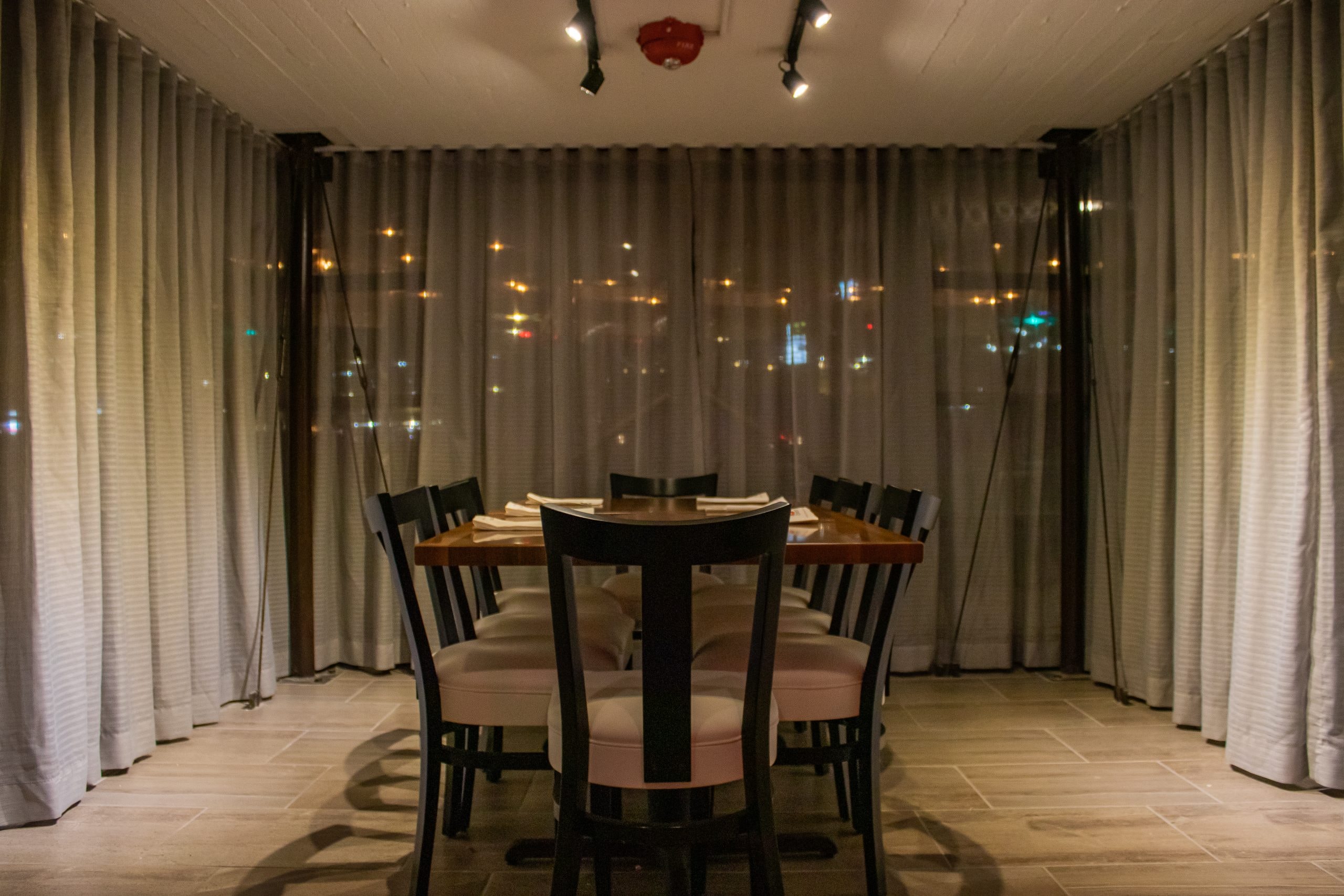 A private dining table set behind floor-to-ceiling curtains at night